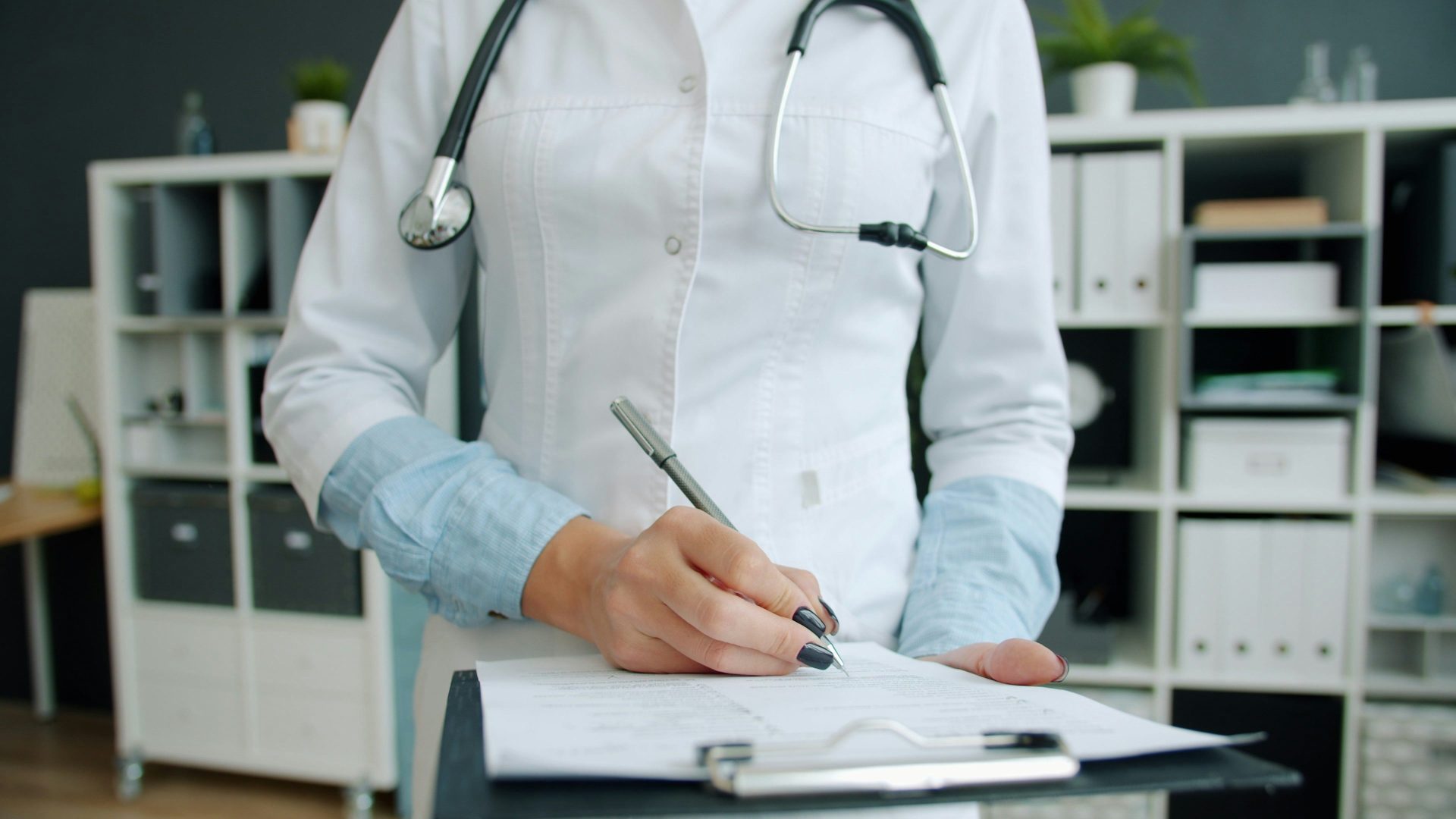 Doctor writing on clipboard in office